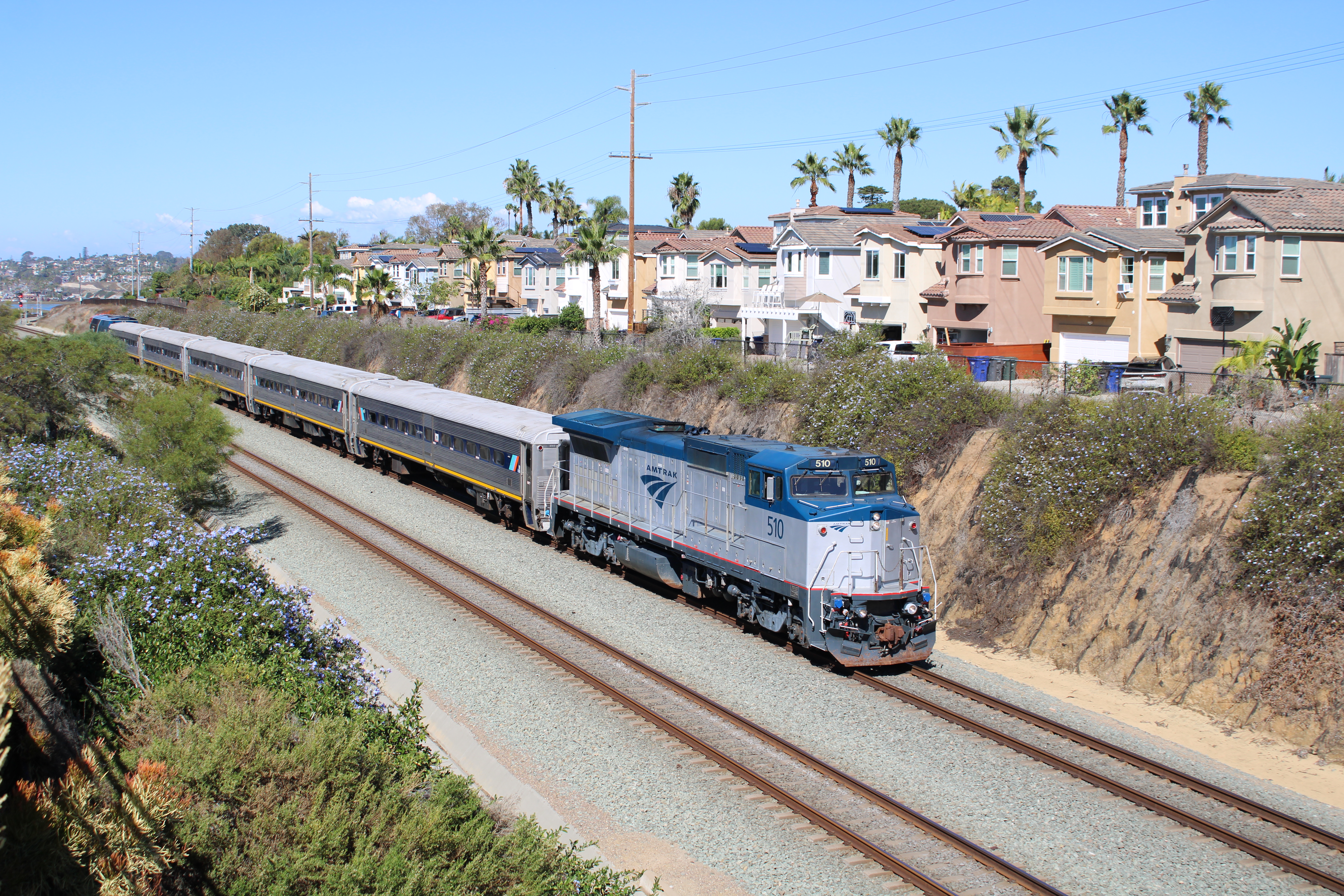 A passenger train runs behind Californian houses