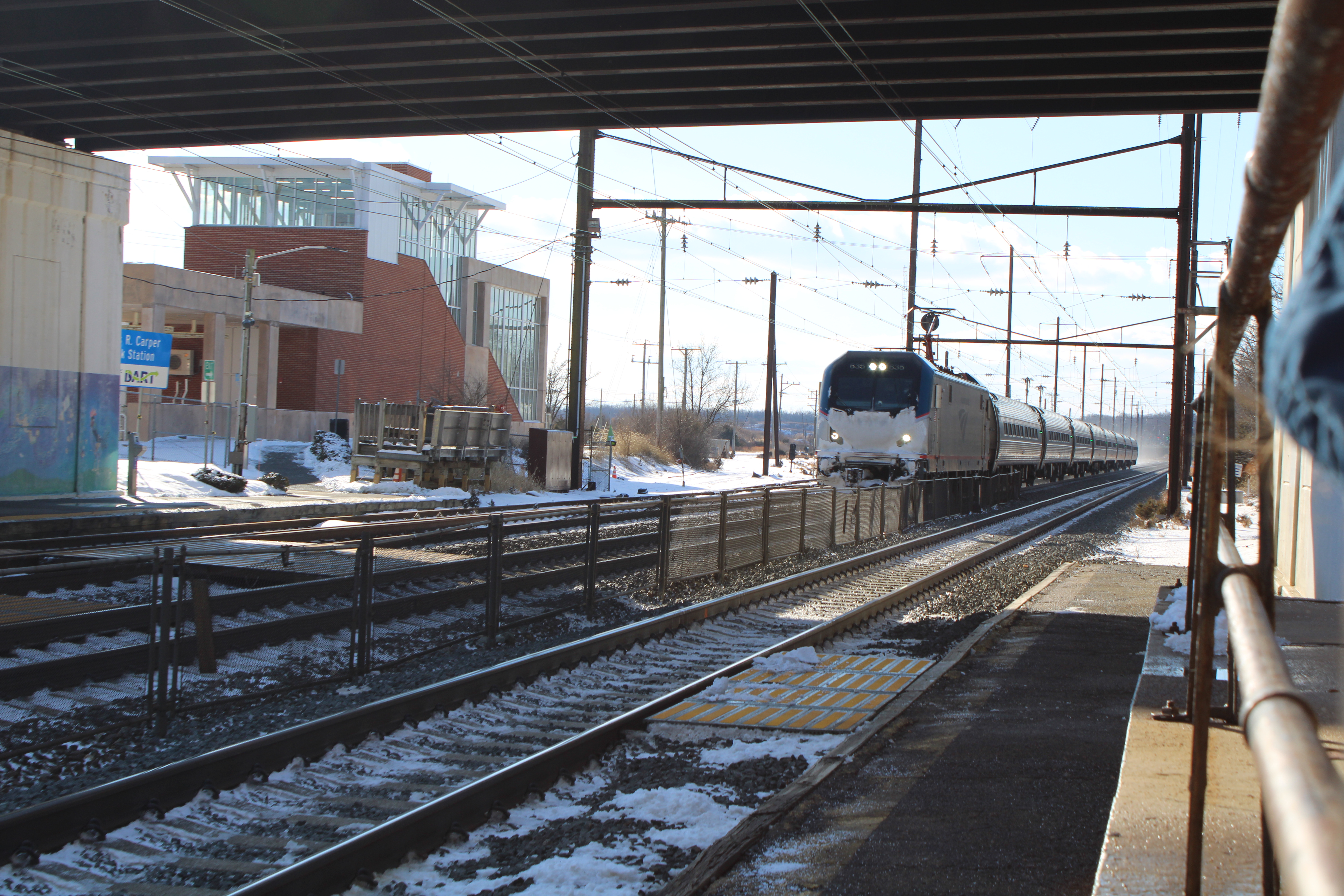 A snowy Amtrak train passes under a bridge